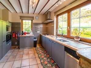 A modern kitchen with a built-in oven, microwave, and gas stove. There is a window with a view of greenery outside.