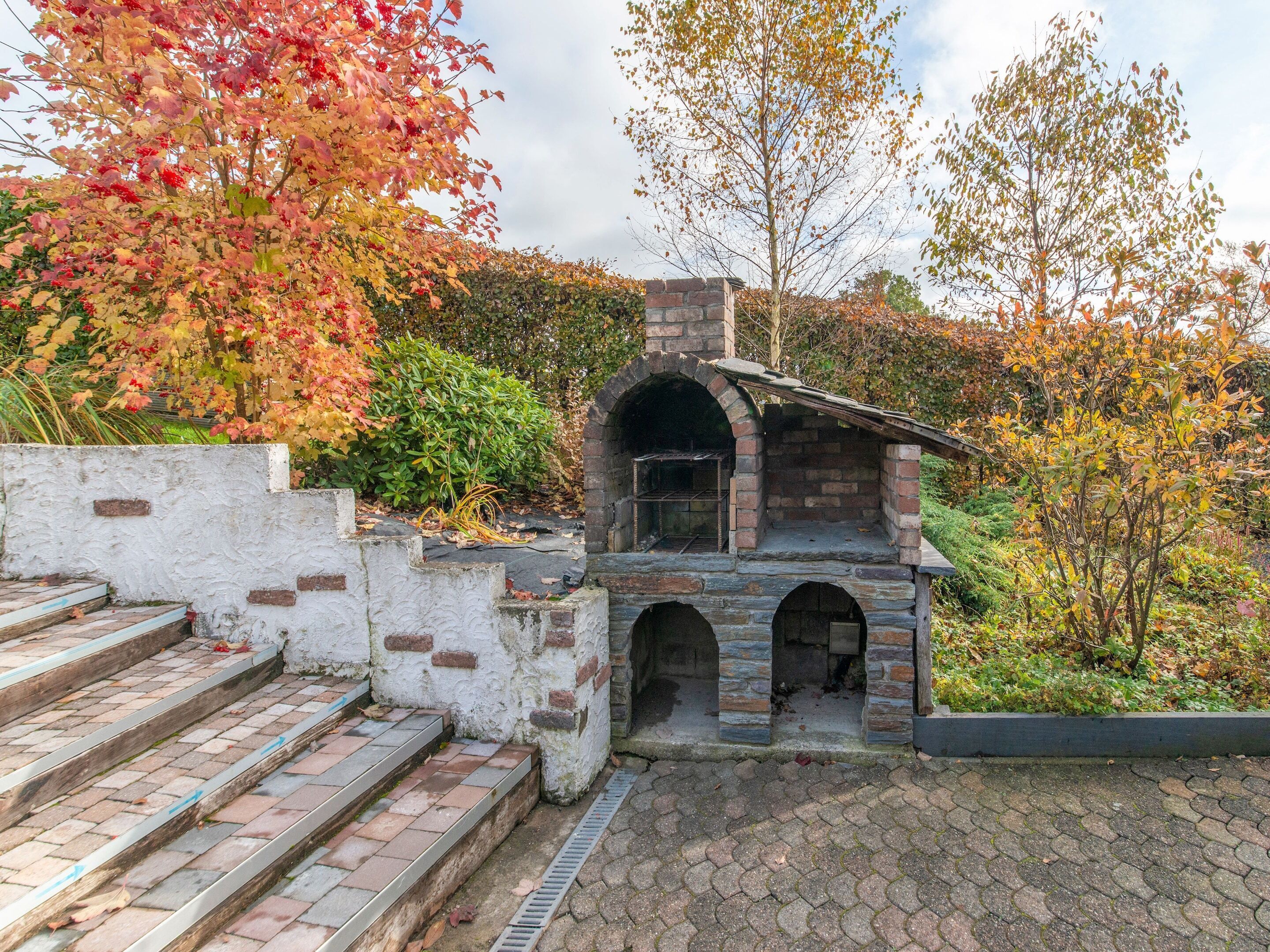 Ein steinernes Gebäude im Freien mit Schornstein, Stufen und einer Ziegelwand im Hintergrund.