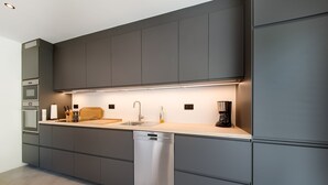 Ett modernt kök med inbyggda vitvaror, diskmaskin och kaffebryggare.