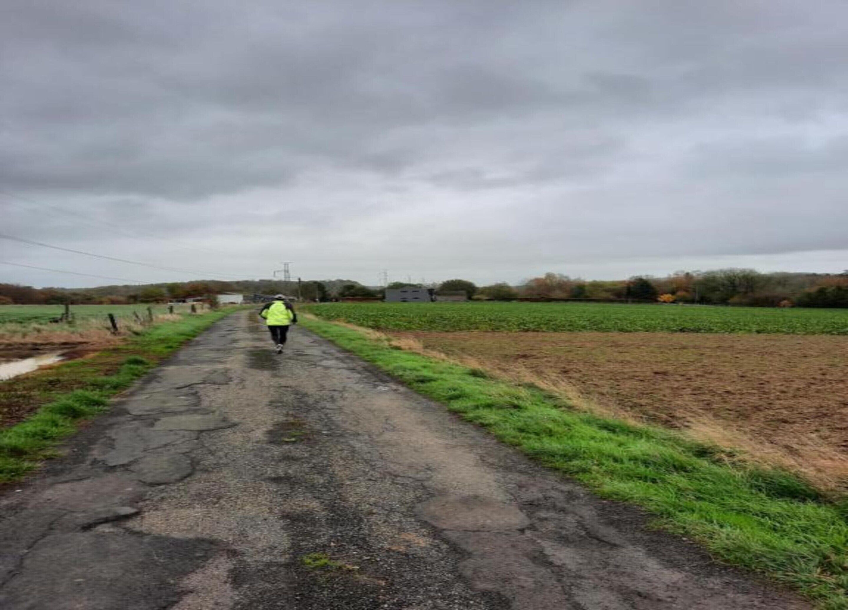 A rural road with a person walking away from the camera.