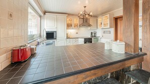 A modern kitchen with a large island, white cabinetry, and a stone backsplash. - Holiday Home in Marche-en-famenne With Garden (Marche-en-Famenne)