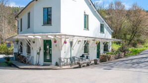 A white building with a covered patio, green shutters, and outdoor seating. - Cozy Country Stay, Stoumont (Stoumont)