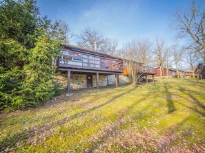 A two-story cabin with a stone foundation and a wooden deck.