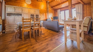 L’intérieur d’un chalet en bois comprend un coin repas, un canapé, un téléviseur et une table avec des paniers.