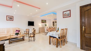 Una sala de estar con sofá, sillas, una mesa de comedor y una cocina al fondo.