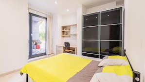 Un dormitorio moderno con cama, escritorio y puerta corredera para el armario.