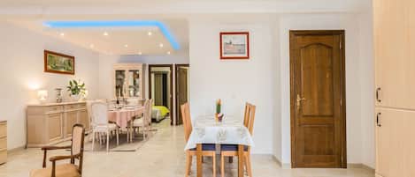 A dining area with a table set for four, a cabinet, and a door.