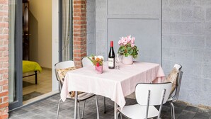 Ett bord dukat med en vinflaska, ett vinglas och en blomsteruppsättning, och stolar placerade runt omkring.