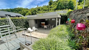 A modern outdoor patio area with a concrete floor, metal railing, and white plastic chairs. - Apartment in Durbuy Near Adventure Park (Durbuy)