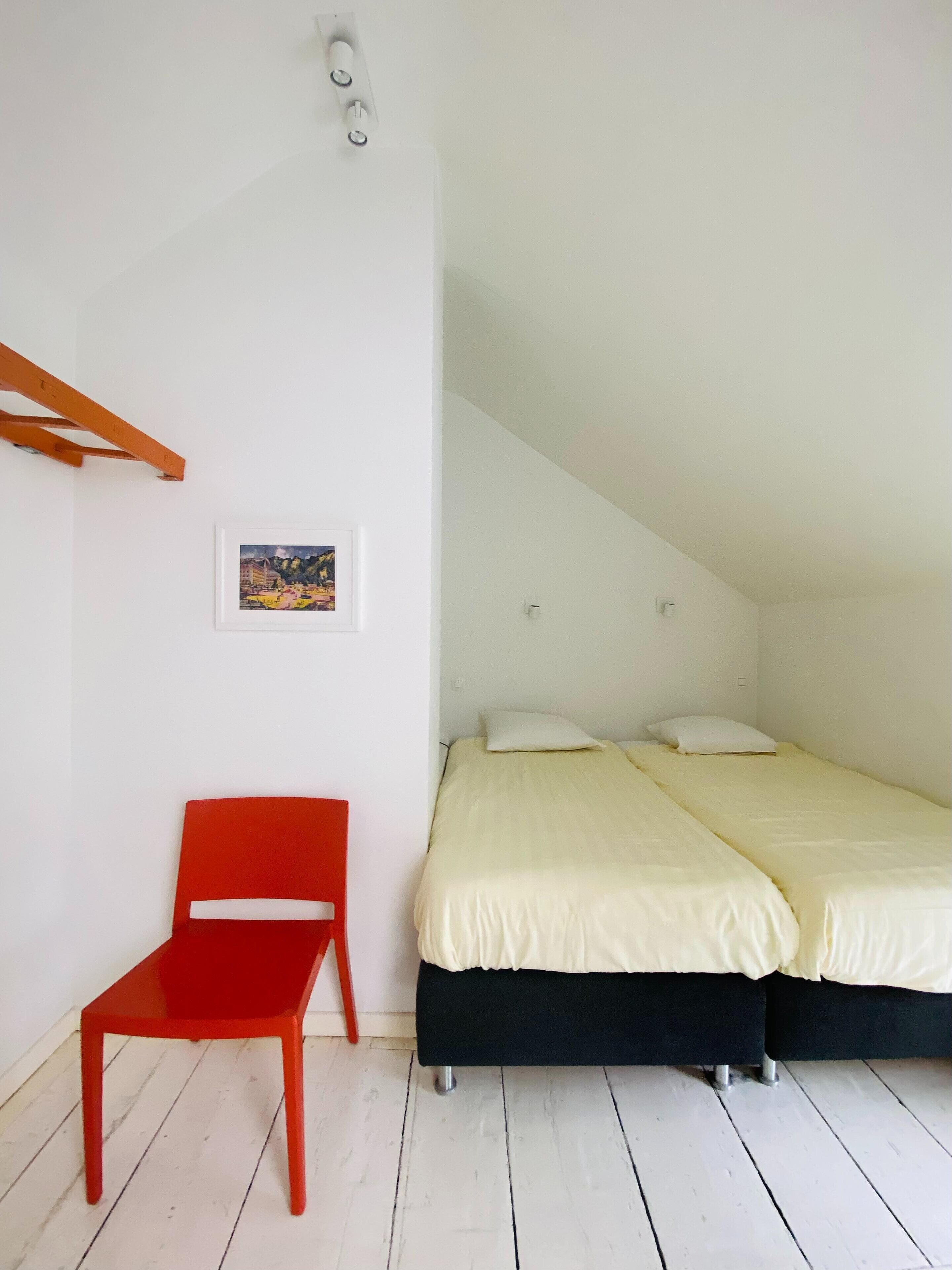 Ein Zimmer mit einem Bett, einem Sessel und einem Bild an der Wand.