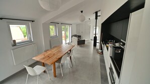 A modern kitchen with a wooden dining table, white chairs, and a black countertop. - Bungalow by Lake Rabais in Virton (Virton)