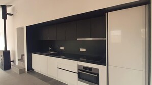 A modern kitchen with white cabinets, black countertops, and a built-in oven. - Bungalow by Lake Rabais in Virton (Virton)
