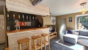 A bar area with stools, a TV, and a wooden ceiling. - House Near Durbuy With Sauna & Bubble Bath (Durbuy)