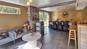 A modern living room with a stone accent wall, a round coffee table, and a sofa with patterned cushions. - House Near Durbuy With Sauna & Bubble Bath (Durbuy)