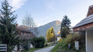 Eine ländliche Straße mit Häusern, einem Berg im Hintergrund und einem klaren Himmel.