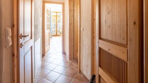 Ein Korridor mit Holztüren und Fliesenboden, der zu einem offenen Bereich mit Blick führt.