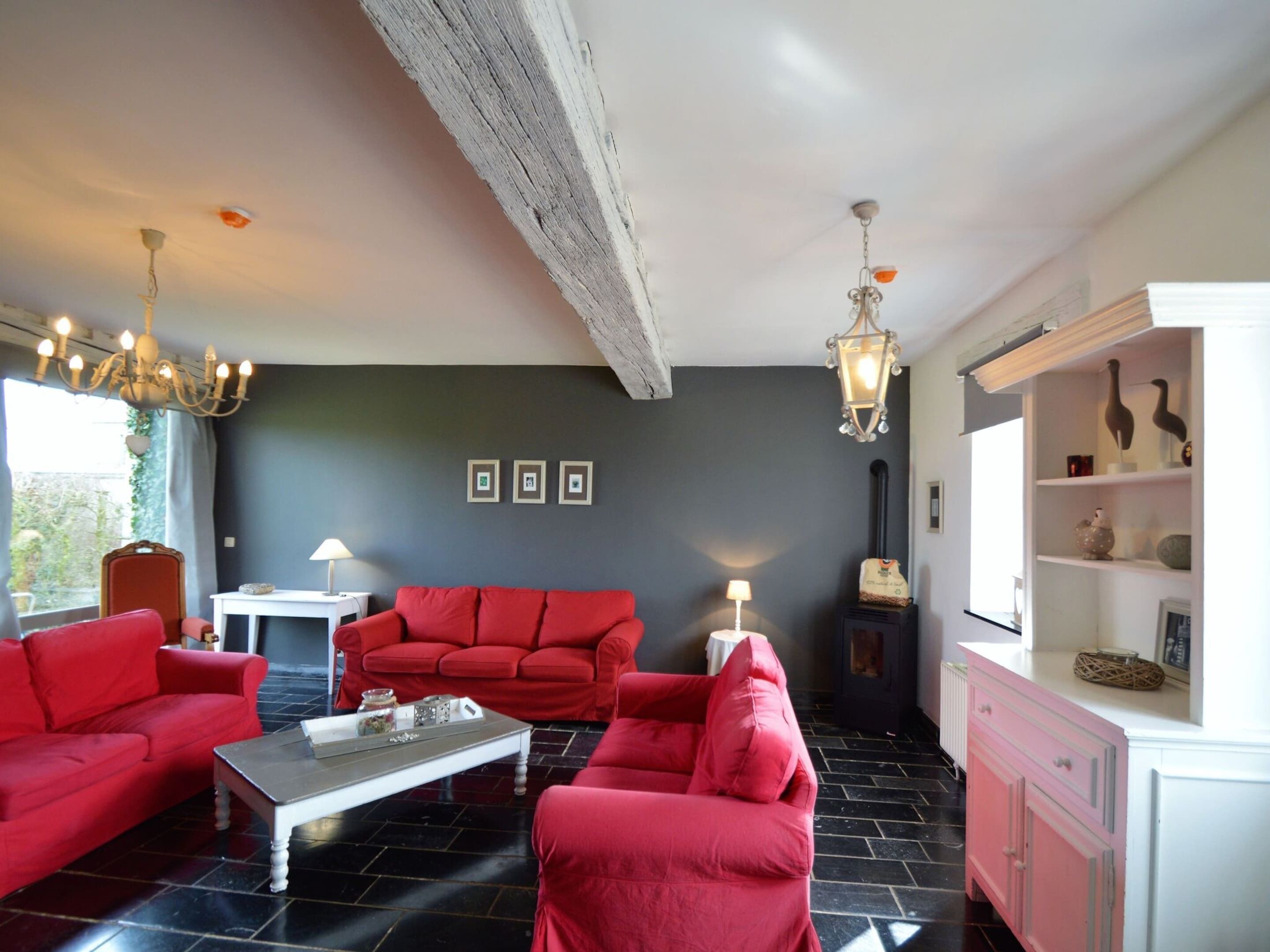 Una sala de estar con un sofá rojo, una mesa de centro blanca y una chimenea.