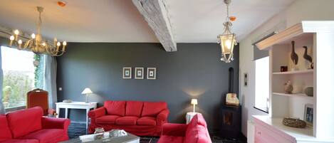 Una sala de estar con un sofá rojo, una mesa de centro blanca y una chimenea.