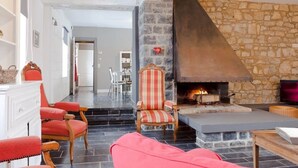Una sala acogedora con chimenea de piedra, sillones tapizados en rojo y un sillón a rayas.