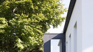 A modern building with a concrete staircase leading to a dark door. - Charming Home With Sauna (Paliseul)