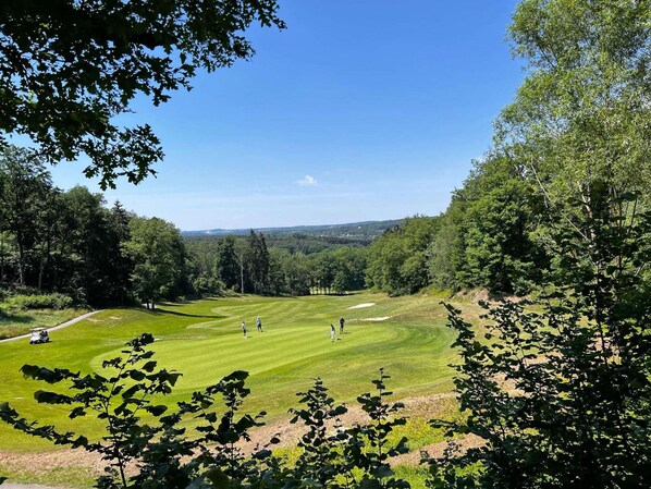 Ein Golfplatz mit freiem Blick auf die Spielbahn, Bunker und die umliegenden bewaldeten Gebiete.