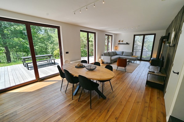 A spacious living area with a wooden dining table, black chairs, a gray sofa, and a fireplace.