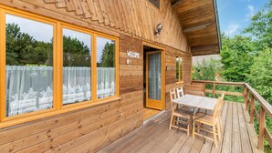 A wooden cabin with a deck, large windows, and a welcome sign. - Holiday Home in Bievre With Garden (Bievre)