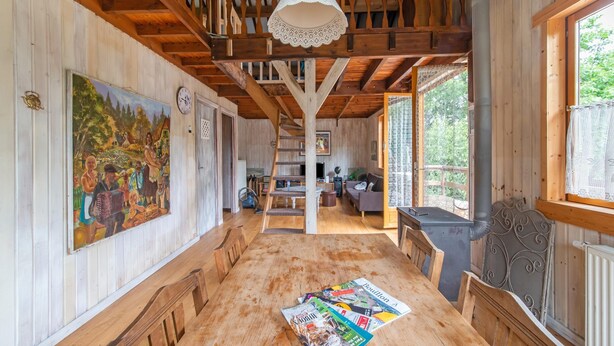 A spacious wooden dining area with a long table, benches, and a chandelier. - Holiday Home in Bievre With Garden (Bievre)