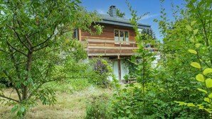 A wooden cabin with a balcony, surrounded by lush greenery. - Holiday Home in Bievre With Garden (Bievre)