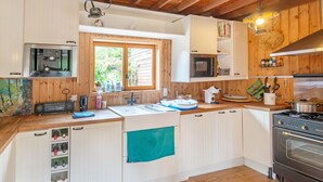 A compact kitchen with wooden cabinets, a built-in microwave, a stove, and a sink. - Holiday Home in Bievre With Garden (Bievre)
