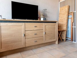 Una habitación moderna con un mueble de madera, un televisor de pantalla plana y una silla de fibras naturales.