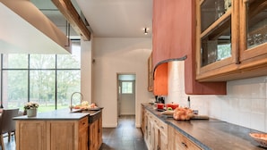 A modern kitchen with wooden cabinets, a central island, and a view of the outdoors. - Beernem Countryside Home (Beernem)