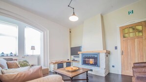 A living room with a fireplace, a sofa, a coffee table, and a TV. - Gite Ma Dame Jeanne in Durbuy With a Sauna (Durbuy)