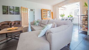 A modern living room with a sofa, chairs, a coffee table, and a bookshelf. - Gite Ma Dame Jeanne in Durbuy With a Sauna (Durbuy)