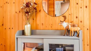 A wooden wall with a mirror, a vase of dried flowers, and a deer figurine on a shelf. - Chalet Le Beau Renard, Heure (Somme-Leuze)