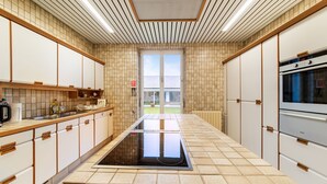 Una cucina moderna con isola centrale, mobili bianchi e una grande finestra.