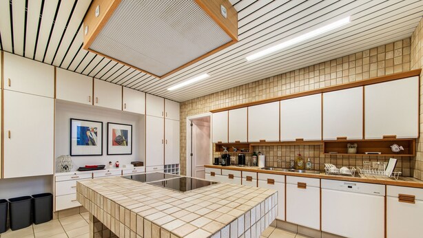 Una cucina moderna con un'isola grande, mobili bianchi e uno schienale piastrellato.