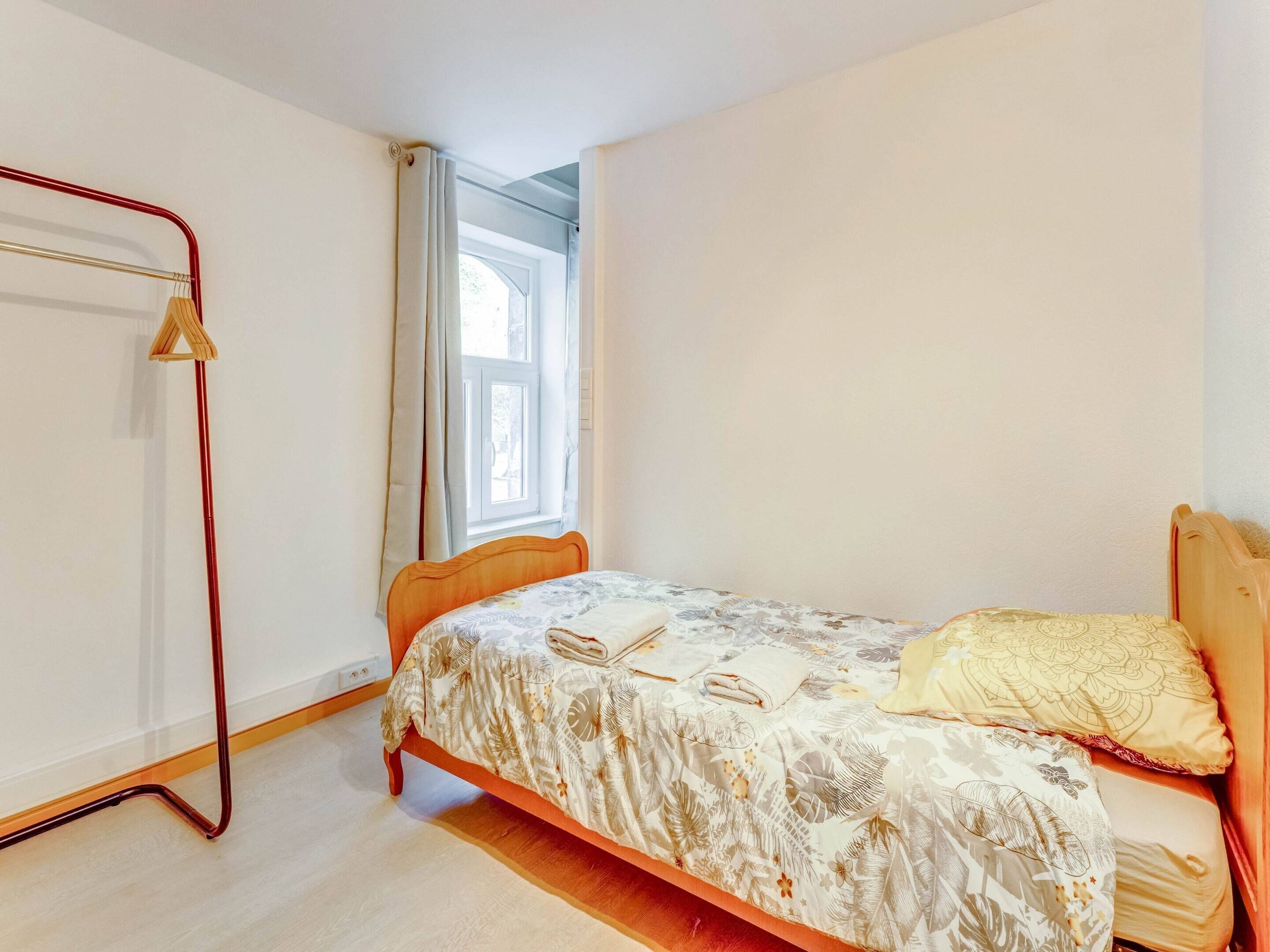 A bedroom with a single bed, a wooden headboard, a floor lamp, and a window with curtains.