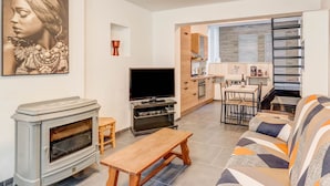 A living room with a fireplace, a television, and a sofa. There is a kitchen area with a dining table and chairs. - Cosy Holiday Home in Hastiere With a Terrace (Hastiere)