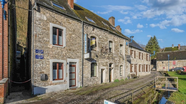 A stone building with a sign for a restaurant, a bicycle parked outside, and a narrow water channel in front. - Cosy Holiday Home in Hastiere With a Terrace (Hastiere)