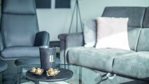 A modern living room with a glass coffee table, a black tumbler, and chocolates. - Cosy Apartment in Oostende With Private Terrace (Ostend)
