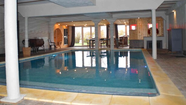 An indoor swimming pool with a clear view of the surrounding area, including a seating area and a fireplace. - Verviers Villa With Sauna (Verviers)
