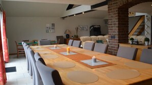 A dining area with a long wooden table, multiple chairs, and candles. - Verviers Villa With Sauna (Verviers)