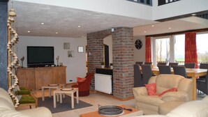 A spacious living area with a television, seating, a fireplace, and a view of the outdoors. - Verviers Villa With Sauna (Verviers)