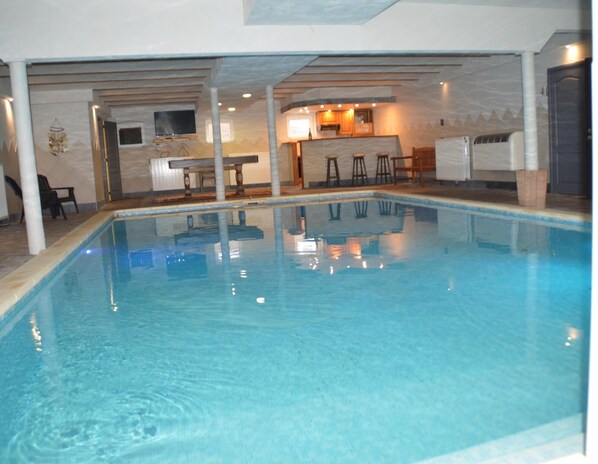 An indoor swimming pool with a kitchen area in the background. - Verviers Villa With Sauna (Verviers)