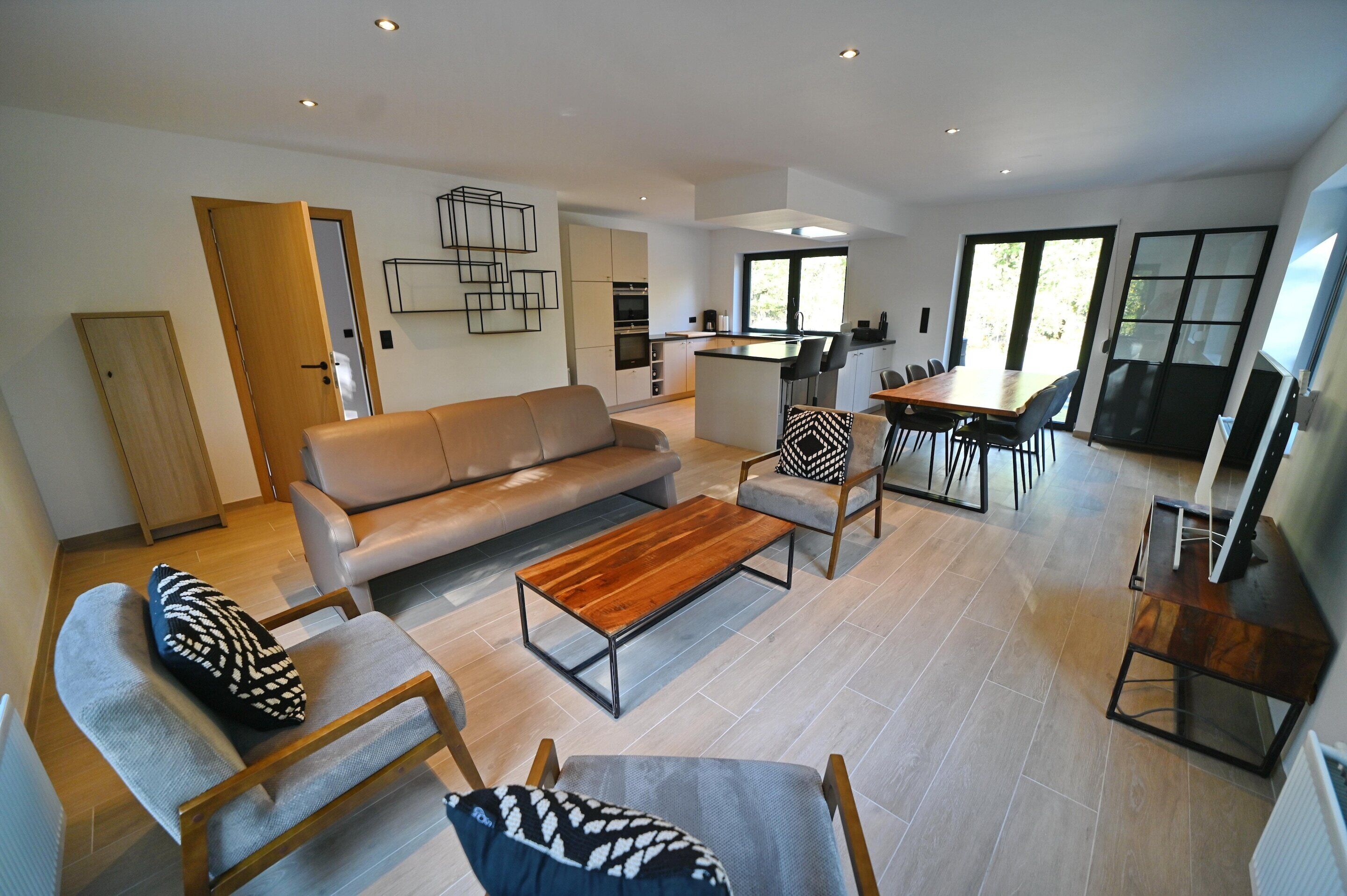A modern living room with a sofa, chairs, a coffee table, and a dining area with a table and chairs.