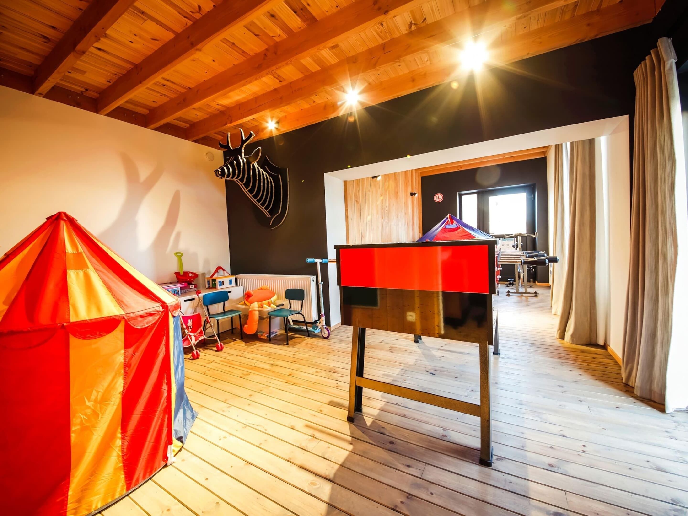 A cozy room with wooden floors, a red and orange tent, a black and red table, and a zebra wall decoration.