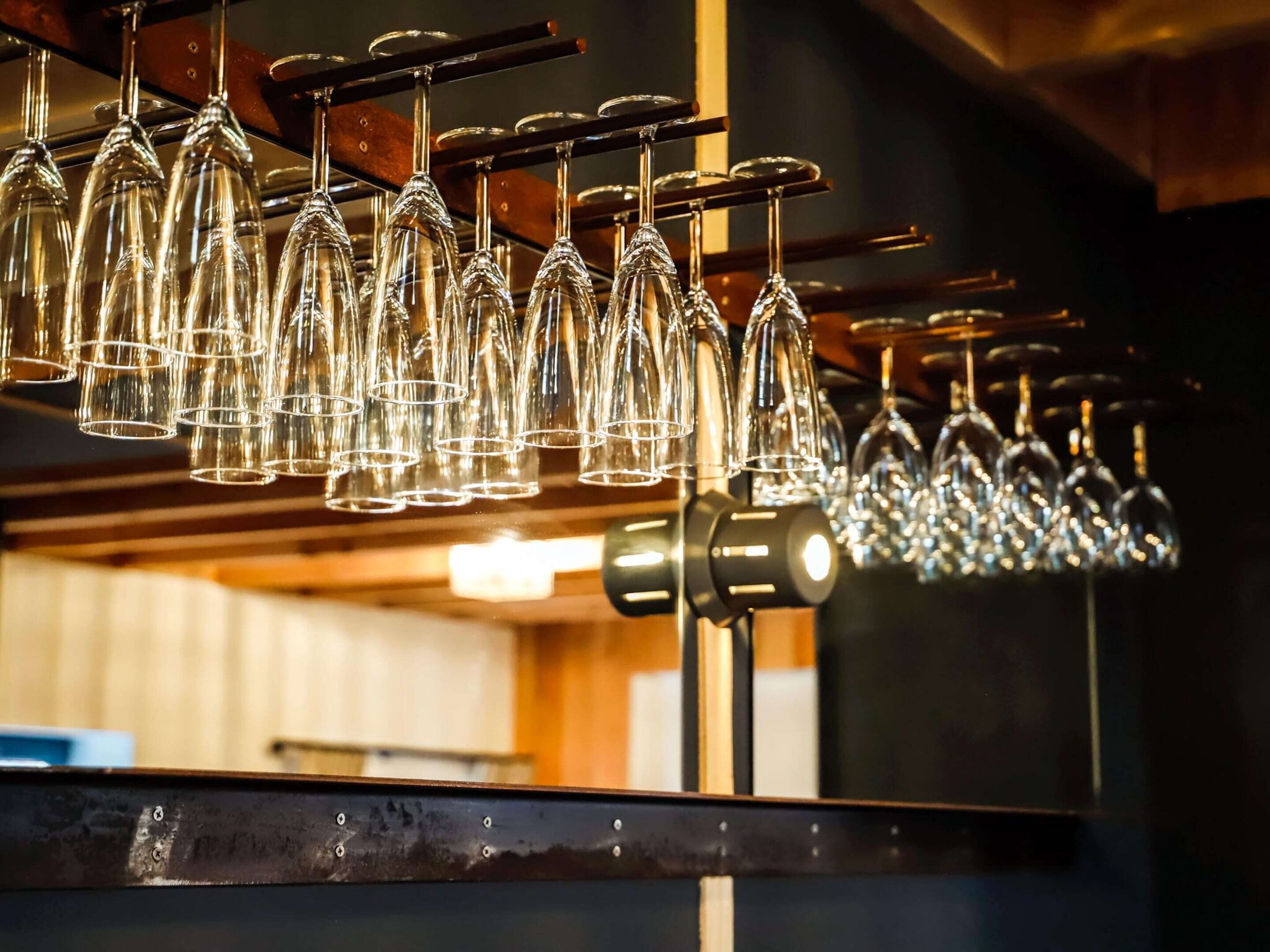 A row of wine glasses hanging from a rack.