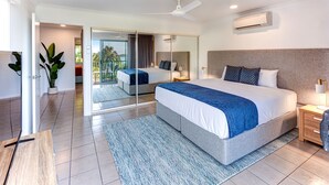 A modern hotel room with a large bed, a ceiling fan, an air conditioning unit, a sliding glass door leading to a balcony, and a potted plant. - Sunset Waters 19 Hamilton Island - golf buggy and transfers (Hamilton Island)
