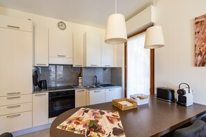 A modern kitchen with white cabinets, a granite countertop, a clock, a kettle, a toaster, and a radio.